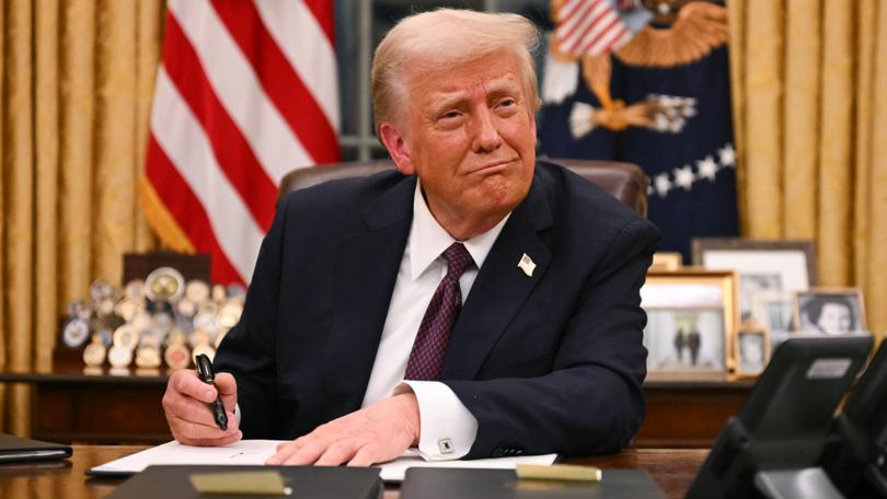 US President Donald Trump signs executive orders in the Oval Office of the White House.