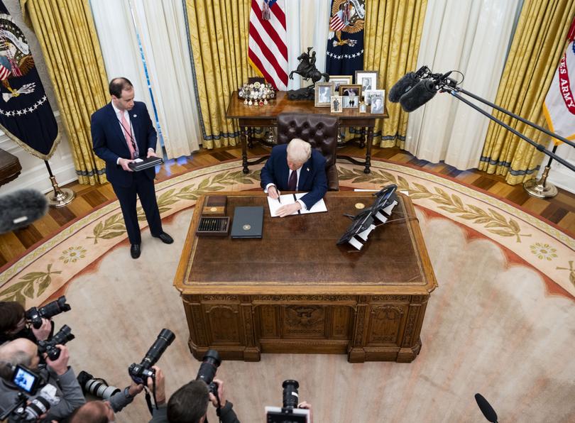 President Donald Trump talks to reporters after signing executive orders in the Oval Office of the White House.