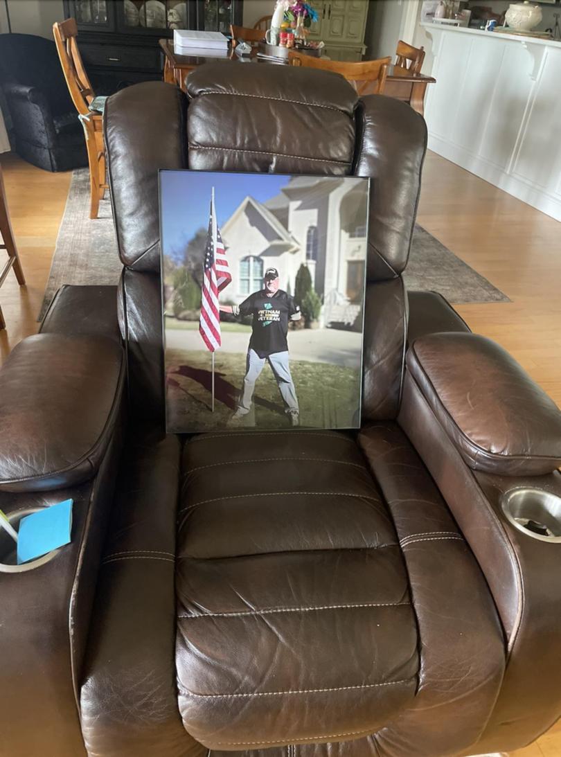 Bill Bryan's recliner holds a 2020 photo of him holding an American flag in front of his home at the time. 