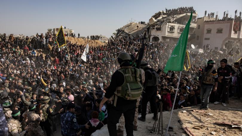 Palestinian civilians and militants gather for the release of hostages, as part of a ceasefire and prisoner exchange deal between Hamas and Israel, in Khan Younis, southern Gaza Strip, 30 January 2025. 