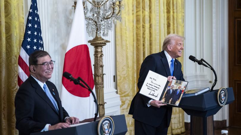 President Donald Trump gives a signed photo to Japanese Prime Minister Shigeru Ishiba during a news conference in the East Room at the White House on Friday. MUST CREDIT: Jabin Botsford/The Washington Post