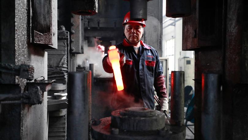 A worker moves a piece of red hot steel at a machinery workshop in Xinghua, in China’s eastern Jiangsu province. 