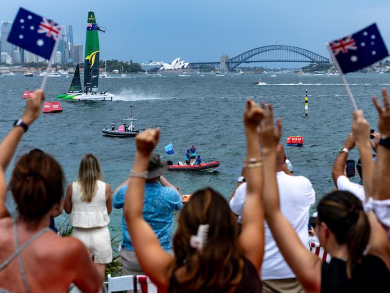 Spectators on Shark Island watch the action as Australia SailGP Team helmed by Tom Slingsby crosses the finish line to win on Race Day 1 of the KPMG Australia Sail Grand Prix in Sydney.