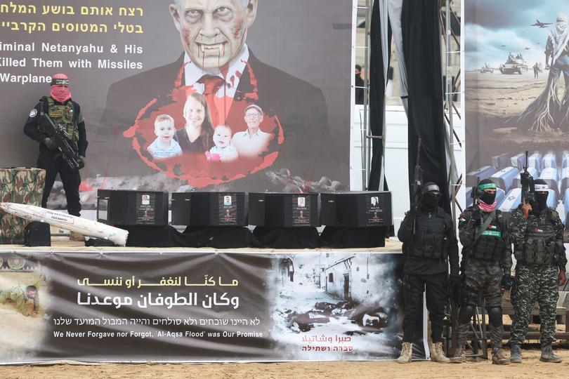 A Hamas militant stands on stage near coffins during the handover of deceased hostages Oded Lifschitz, Shiri Bibas and her two children Kfir and Ariel Bibas, seized during the deadly October 7, 2023 attack.