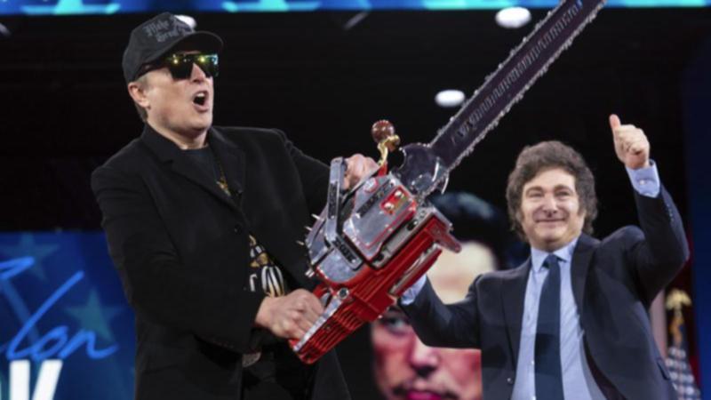 Elon Musk holds up a chainsaw he received from Argentina's President Javier Milei (right) at CPAC. (AP PHOTO)