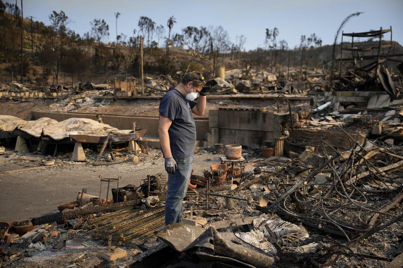 Kevin Marshall sifts through his mother's fire-ravaged property in the the Palisades Fire in the Pacific Palisades neighborhood of Los Angeles, Saturday, Jan. 11, 2025. (AP Photo/John Locher)