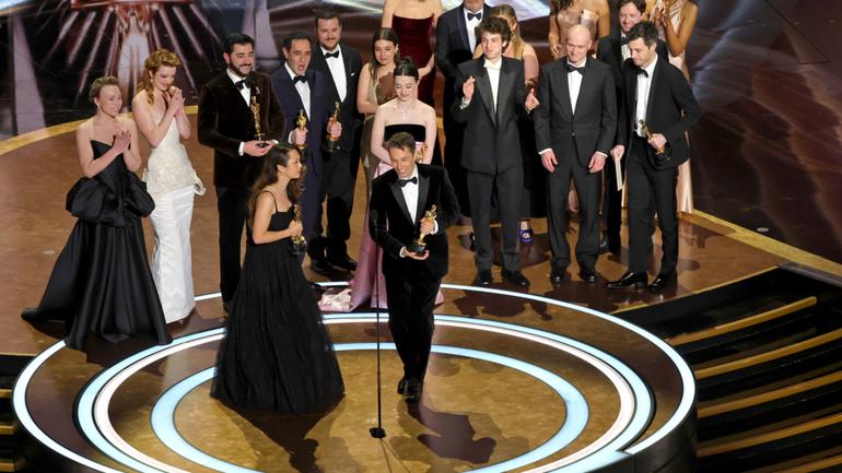 The cast and crew from Best Picture winner Anora celebrate on stage. 