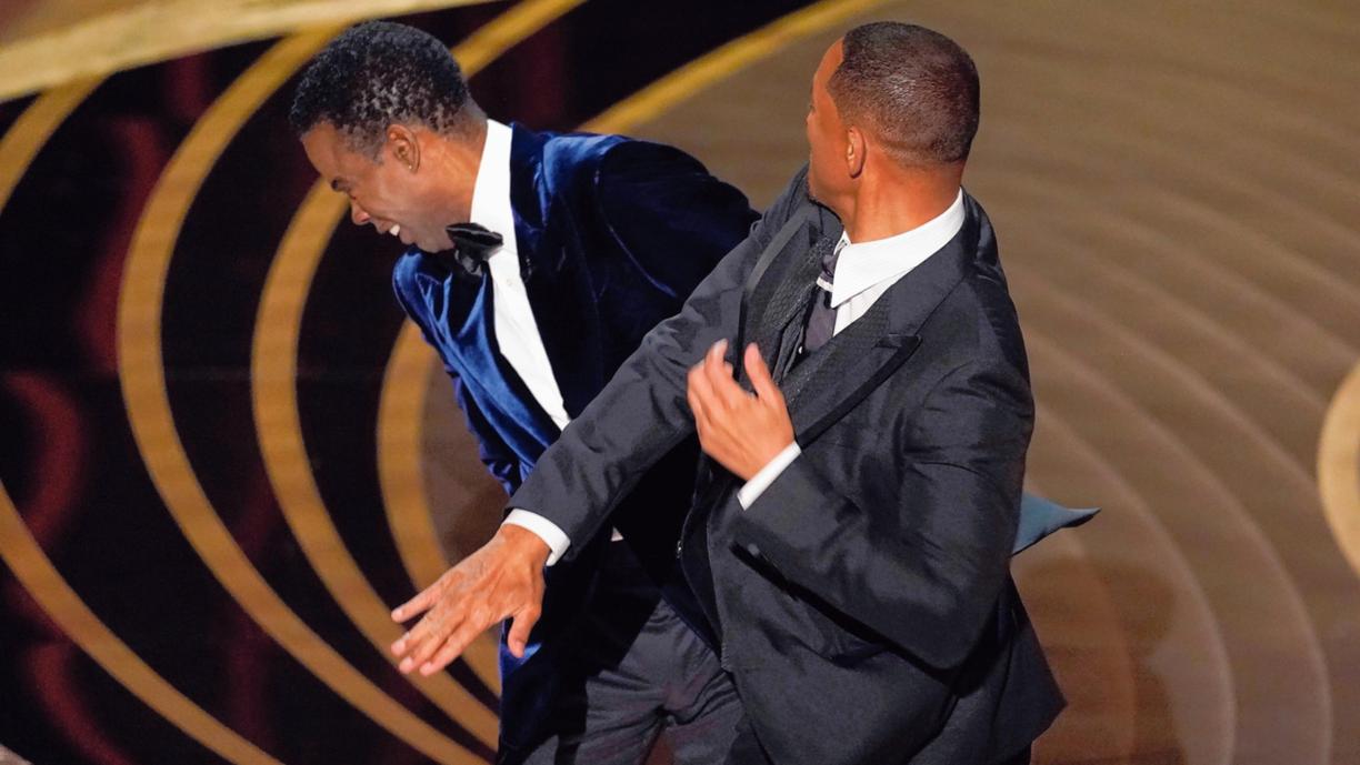 Will Smith, right, hits presenter Chris Rock on stage while presenting the award for best documentary feature at the Oscars.