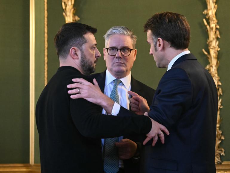 Ukraine's President Volodymyr Zelensky, Britain's Prime Minister Keir Starmer and France's President Emmanuel Macron embrace during the summit at Lancaster House/