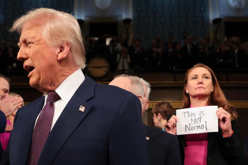 Rep. Melanie Stansbury (D-NM) holds a sign reading "This is not normal" at the U.S. Capitol before Mr Trump's speech.