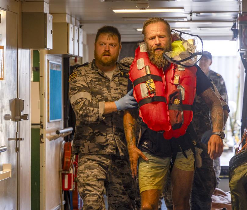 Chief petty officer medic Peter Gough leading solo rowboat adventurer Aurimas Mockus to the ship's hospital onboard HMAS Choules.