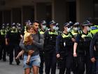 A man holding a child walks Victoria Police as people participate in the Eureka Freedom Rally anti-vaccination and anti-mandatory vaccination protest in Melbourne, Saturday, December 4, 2021.