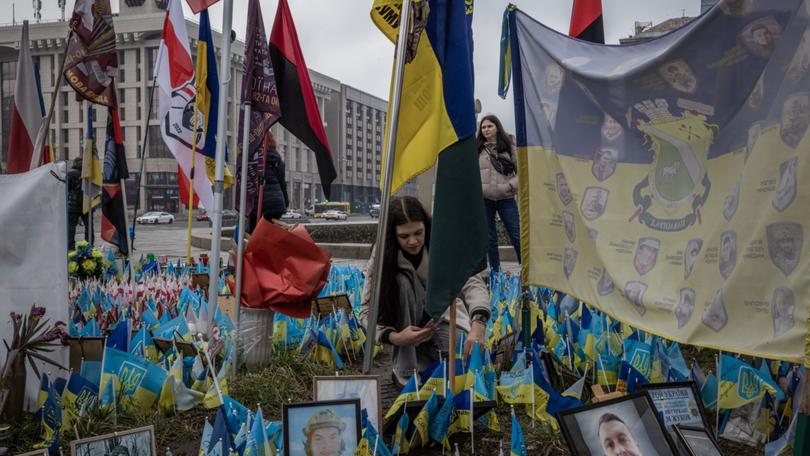 From left, Oksana Harei, 26, and Karina Harei, 25, look for a place to put flags near the relevant brigade at a makeshift memorial in Kyiv for soldiers killed since the start of Russia’s full-scale invasion of Ukraine in 2022. 