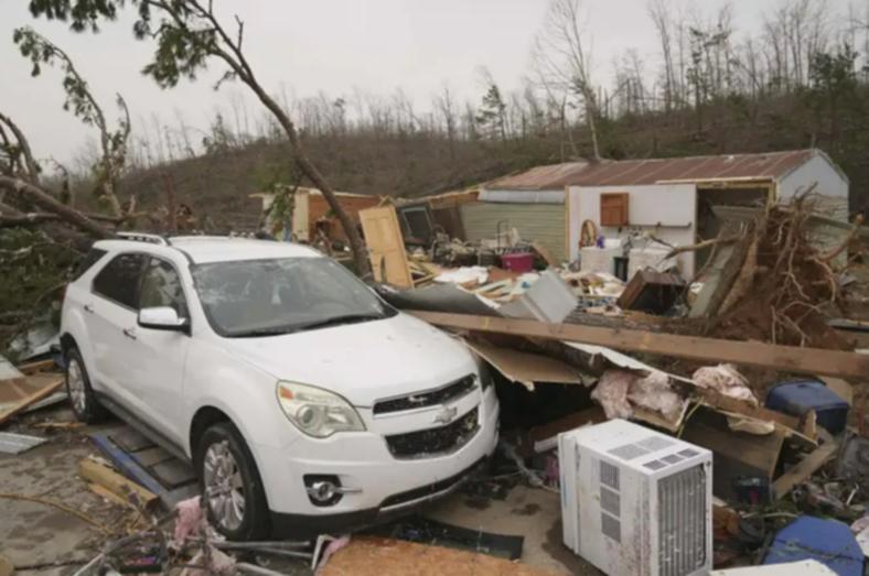 A vehicle sits in front of a damaged home and debris from a severe storm Saturday, March 15, 2025, in Wayne County, Mo.