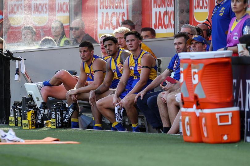 West Coast players watch on from the bench.