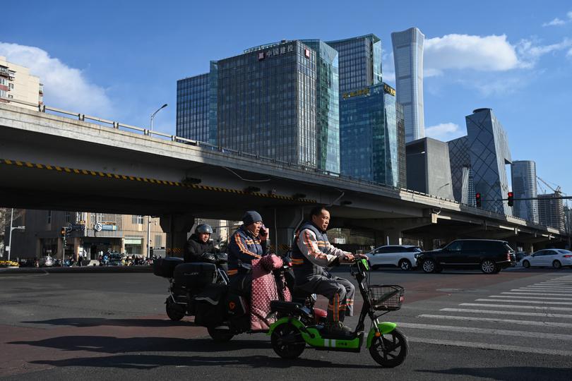 People ride scooters on a street at the central business district in Beijing.