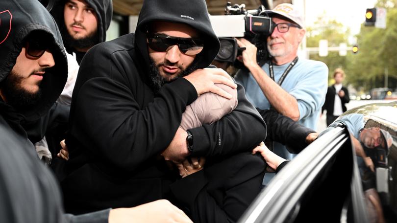 Sarah Abu Lebdeh (centre) is protected by supporters as she departs the Downing Centre Local Court, Sydney.