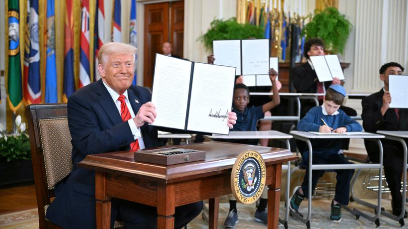 US President Donald Trump holds an executive order after signing it in the East Room of the White house in Washington, DC, March 20, 2025. 