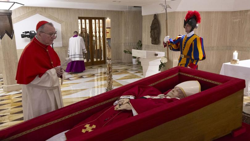 Vatican Secretary of State Cardinal Pietro Parolin, left, prays in front of the body of Pope Francis.