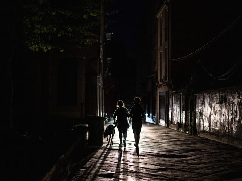 Pedestrians walk on an unlit street during a power outage in Ourense, Spain, on Monday, April 28.