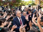 Prime Minister Anthony Albanese, with WA Premier Roger Cook in the background, gives high fives to Winthrop Primary School students in Perth.