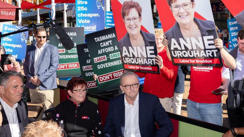 Liberal volunteers got their signs behind Anthony Albanese while he was campaigning in Braddon with deputy Richard Marles and candidate Anne Urquhart.