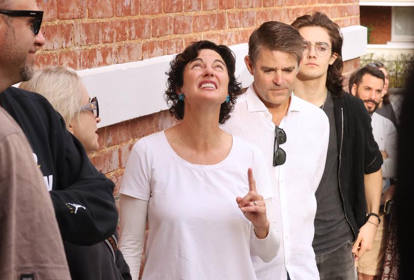 Independent member for Curtin Kate Chaney points to the sky as rain starts to fall while waiting in line to vote at West Leederville Primary School.