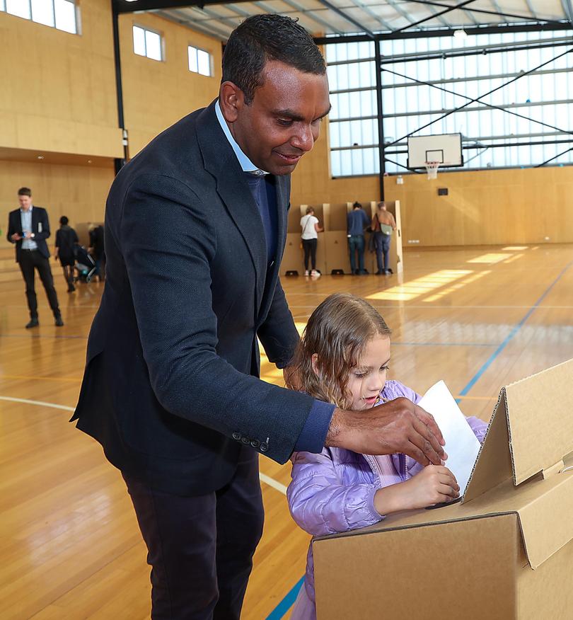 Liberal candidate for the seat of Macnamara, Benson Saulo, casts his vote with his daughter Anais at Port Melbourne Primary School.