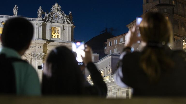 Faithful gathered in St. Peter's Square watch black smoke ouring out of the chimney atop the Sistine Chapel on the first day of the conclave to elect a new pope.