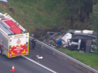 A driver is dead and a passenger fighting for life after a car towing a caravan plunged into a creek off a major highway.