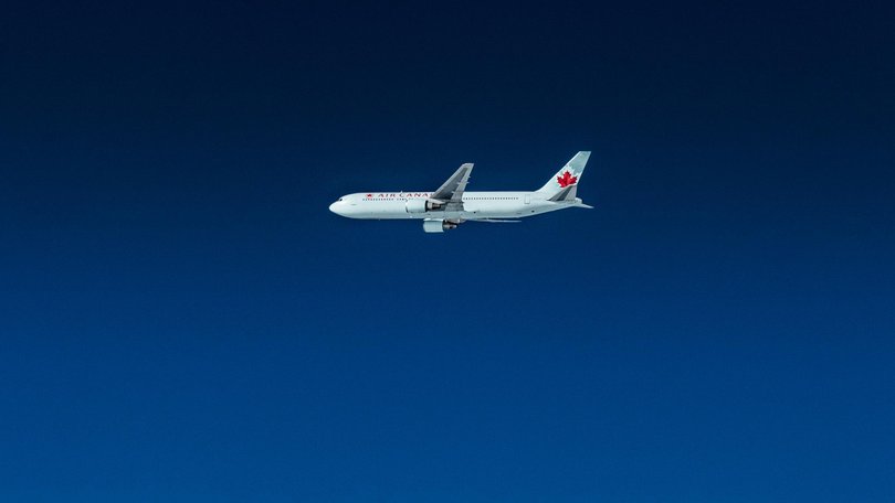 An Air Canada Boeing flying in the deep blue sky.