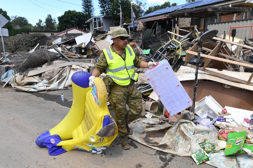 A member of the ADF (Australian Defence Force) is seen helping in the clean up of flood affected properties in the suburb of Goodna in Ipswich, Tuesday, March 8, 2022. Queensland is looking at a damage bill of more than $2.5 billion following the flood disaster that has claimed 13 lives. (AAP Image/Darren England) NO ARCHIVING