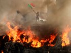 A man waves a Mexican flag as smoke and flames rise from a burning vehicle during a protest against federal immigration sweeps, near Los Angeles City Hall in downtown Los Angeles, California, U.S. June 8, 2025.   