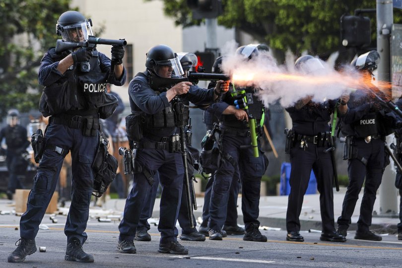 Police fire non-lethal weapons at activists hiding behind a makeshift barricade during protests sparked by immigration raids in Los Angeles, California, USA, 08 June 2025.