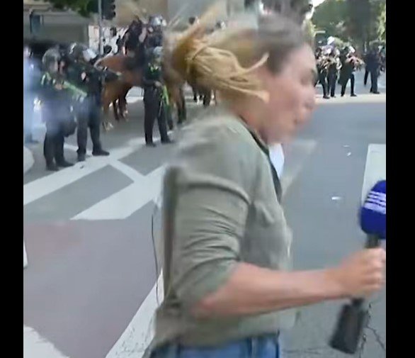 Lauren Tomasi reacts after being shot with a rubber bullet.