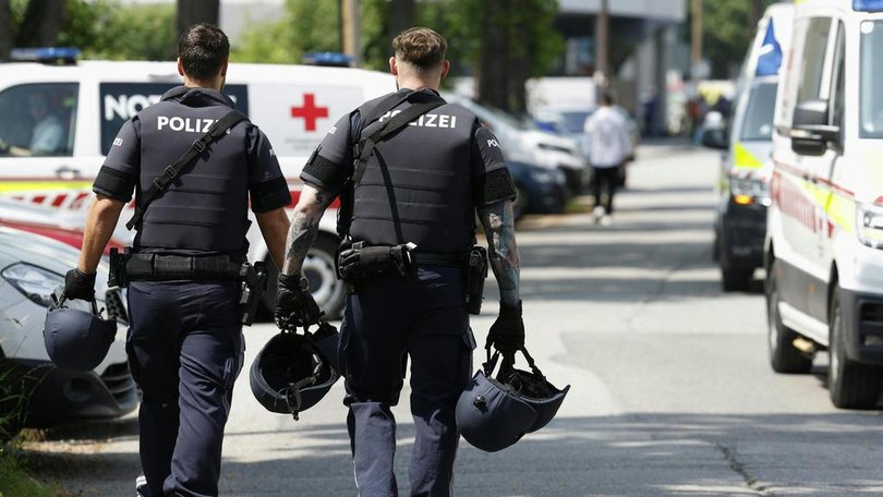 Two policemen walk past ambulance cars in a street close to a school where, according to reports, several people died in a shooting, on June 10, 2025 in Graz, southeastern Austria.