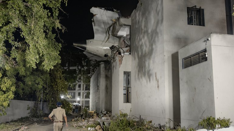 The tail of the Air India flight that crashed shortly after takeoff protrudes from a medical college hostel on June 12, 2025 in Ahmedabad, India. 