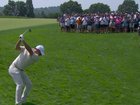 Rory McIlroy hits a shot over a small crowd directly in front of him.