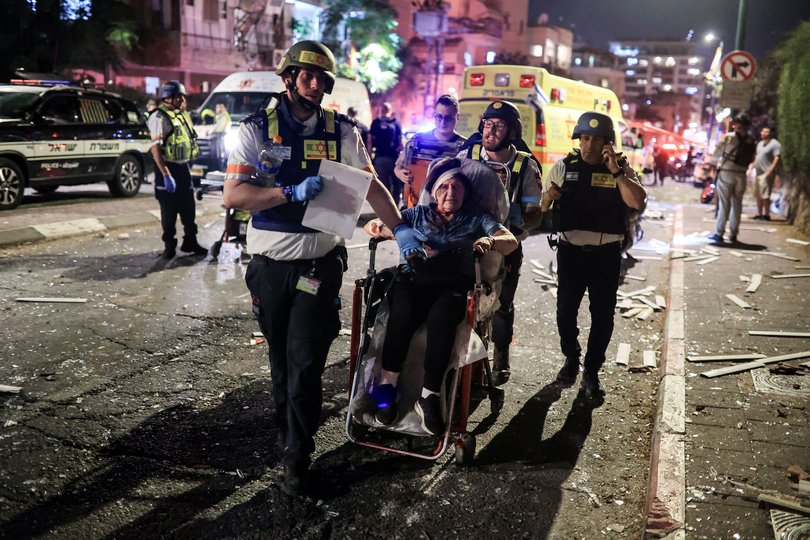 Rescue personnel evacuate a wounded woman at an impact site following missile attack from Iran on Israel, in Ramat Gan, Israel.