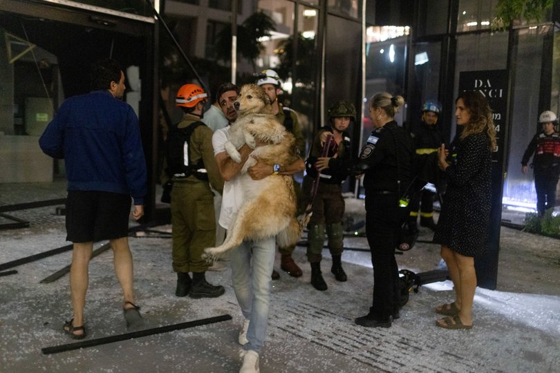 A resident carries their dog after a building was hit by Iranian missiles in Tel Aviv, Israel, on Friday, June 13, 2025.