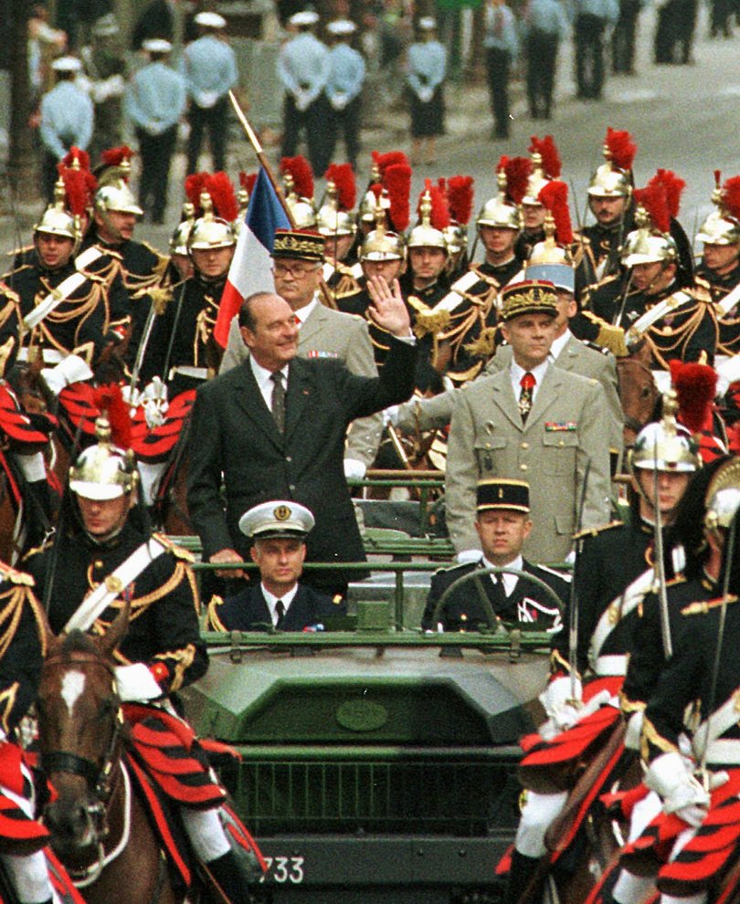 French President Jacques Chirac, left, waves from the command car to the crowd before the Bastille Day military parade in 1999.