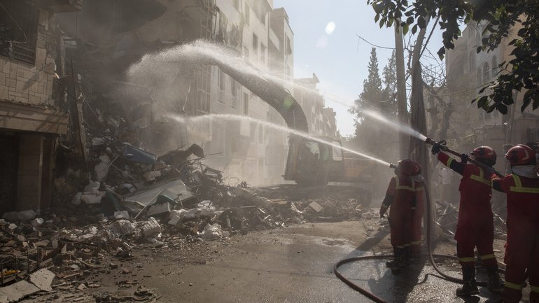 Firefighters extinguish a fire in a building that was destroyed in an Israeli attack on June 13.