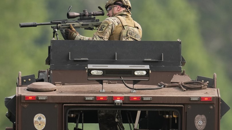 A law enforcement officer trains his rifle towards a house as the officers search for shooting suspect, Vance Boelter, in Belle Plaine, Minnesota.