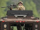 A law enforcement officer trains his rifle towards a house as the officers search for shooting suspect, Vance Boelter, in Belle Plaine, Minnesota.