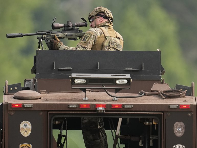 A law enforcement officer trains his rifle towards a house as the officers search for shooting suspect, Vance Boelter, in Belle Plaine, Minnesota.