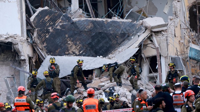 Rescuers sift through the debris of a damaged building in the Israeli city of Tel Aviv after a fresh barrage of Iranian rockets on June 16, 2025.