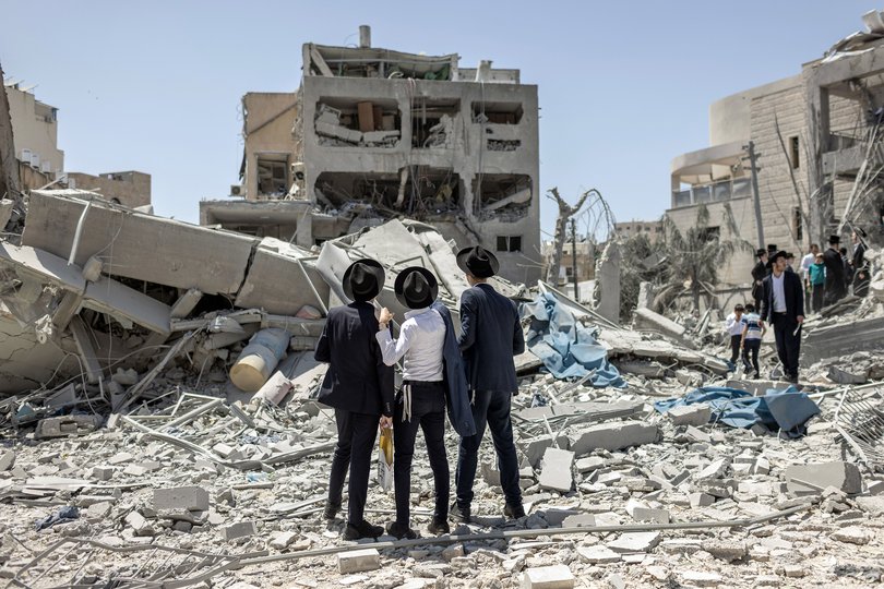 Men look over the damage to a school building in Bnei Brak, Israel, east of Tel Aviv, after an Iranian missile strike.
