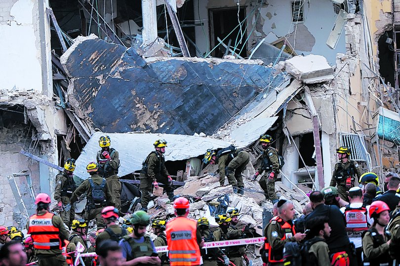 Rescuers sift through the debris of a damaged building in the Israeli city of Tel Aviv after a fresh barrage of Iranian rockets on June 16, 2025.