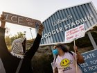 A small group of demonstrators protests outside the entrance of Dodger Stadium.