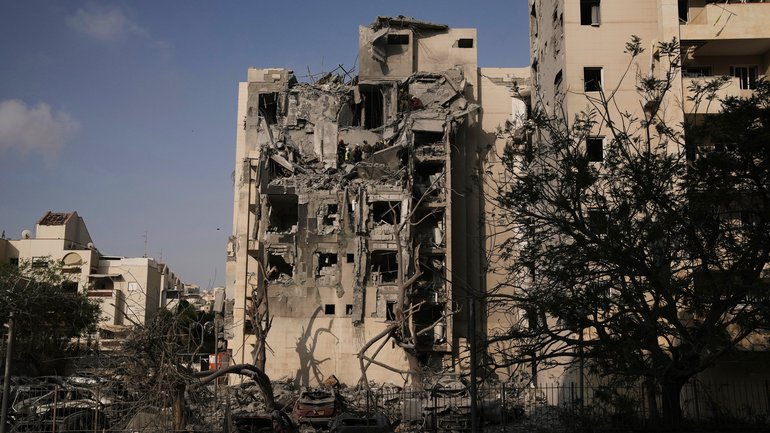 Israeli soldiers and a rescue team search for survivors amid the rubble of residential buildings.